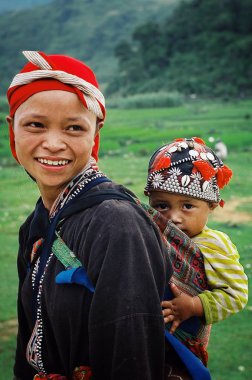 Sapa / Vietnam - 5 Ağustos 2010: şirin çocuğunu bir pirinç alanının yanındaki yüksek rütbeli puslu dağlar ile Genç Anne