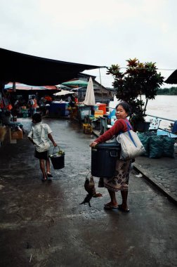 Pakse / Laos - 06 Temmuz 2011: ev ile biraz tavuk ve pirinç bir kapsayıcı sokak piyasadan yürüyen yerel kadın