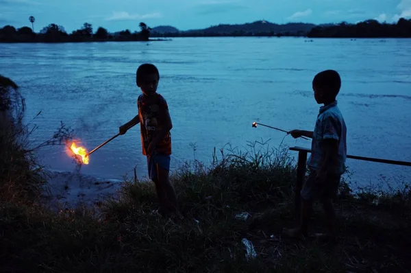 2011年7月06日 为筹备一个宗教庆典 两个年轻男孩在湄公河沿岸的上座部佛教修道院周围点燃蜡烛 — 图库照片
