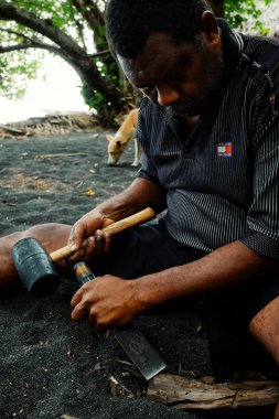 Olal Köyü, Ambrym Island / Vanuatu Cumhuriyeti - 9 Temmuz 2016: yerel sanatçı siyah volkanik kum tropikal deniz okyanus plaj üzerinde küçük bir ahşap kabile heykel oyma
