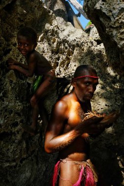 Walarano Köyü, Malekula Island / Vanuatu Cumhuriyeti - 9 Temmuz 2016: bir genç Sevimli çocukla bir mağarada geleneksel sürtünme matkap yolda ışık için ateşe üfleme yerel kabile adam