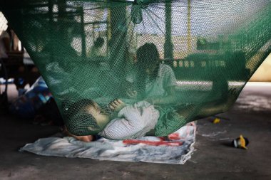 Angkor Wat, Siem Reap / Kamboçya - 22 Ekim 2011: cibinlik arka planda çalışan annesi ise, Uyuyan güzel güzel genç bir çocuk