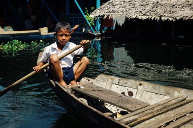 Yasadışı topluluk, Tonle Sap Gölü / Kamboçya - 22 Ekim 2011: yerel okul çocuk öğrenci kürek çekmeye ev onun Kano kayan Tepedeki ev yerleşim önünde gölde, dersten sonra