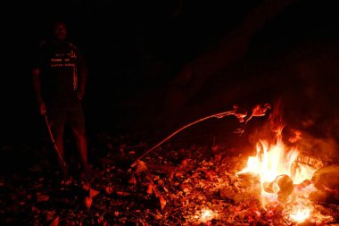 Lolits Köyü, Espiritu Santo Adası / Vanuatu Cumhuriyeti - 10 Ağustos 2016: yemek yemek için bekleyen gece şenlik ateşi bir ağacın altında oturan yerel köylü adam pişmiş olması