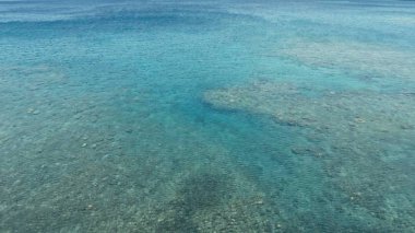 harika bir mercan kayalığı sakin hava düz su ve inanılmaz renkli deniz okyanus yatağına küçük bir uzaktan izole tropikal ada etrafında çarpıcı havadan dron görüntü