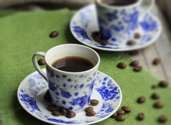 Cup of coffee and coffee seeds on a plate with blue rose