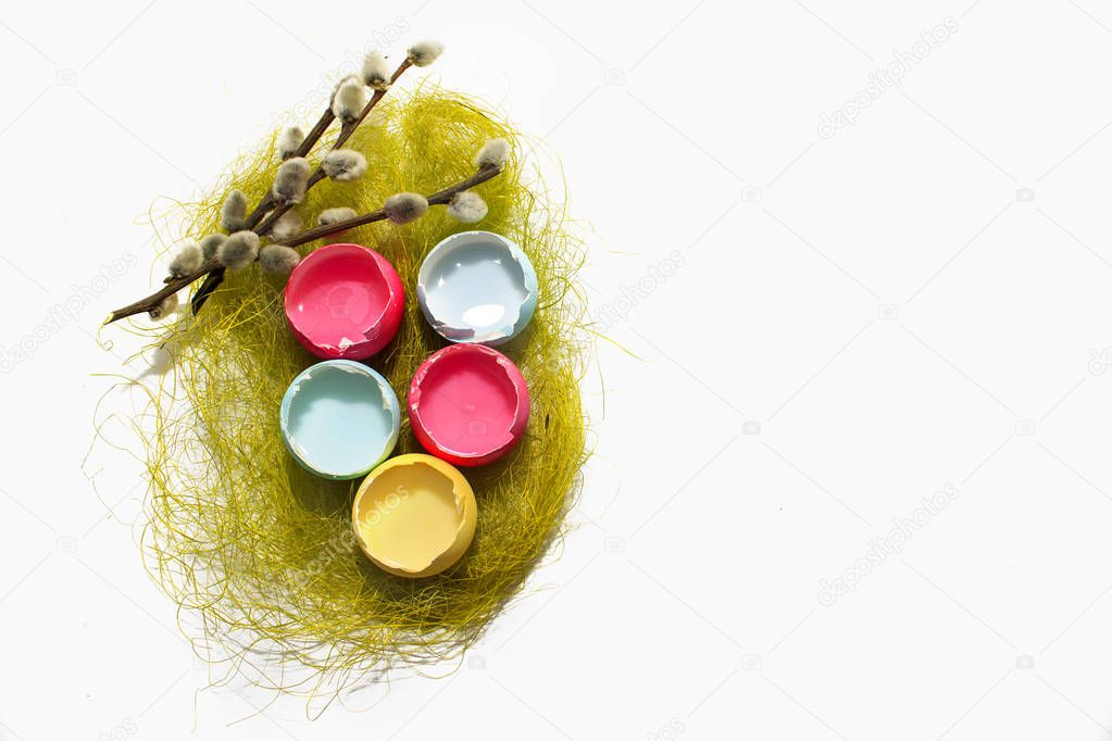colored Easter eggs (red, yellow, blue) on a white background and a willow twig