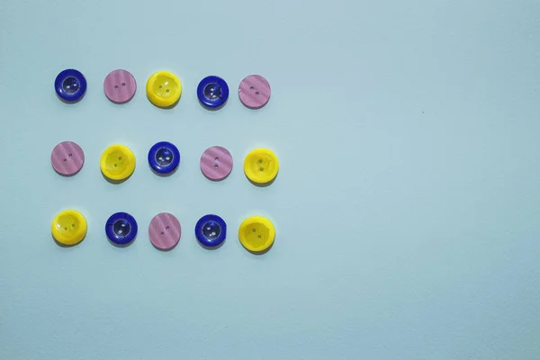 Collection de divers bouton de couture multicolore sur fond bleu. Boutons jaunes, violets, bleu foncé. Minimalisme. Accessoires de couture. Flatlay, place pour le texte — Photo