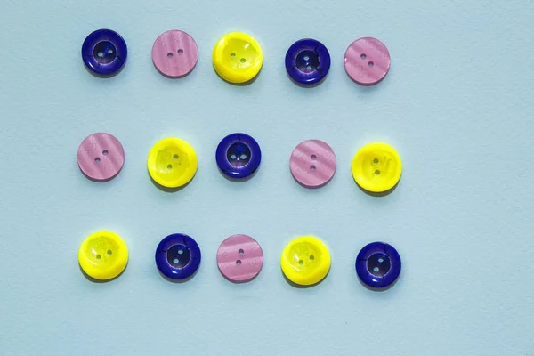 Колекція різнокольорових швейних гудзиків на синьому фоні. Жовті, фіолетові, темно-сині кнопки. Мінімалізм. Швейна фурнітура. Квартира, місце для тексту — стокове фото