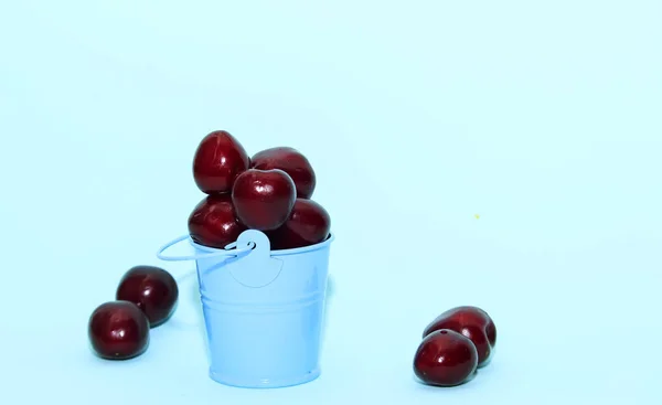 Cereja fresca em balde azul sobre fundo de papel azul. Cerejas frescas e maduras. Cerejas doces . — Fotografia de Stock