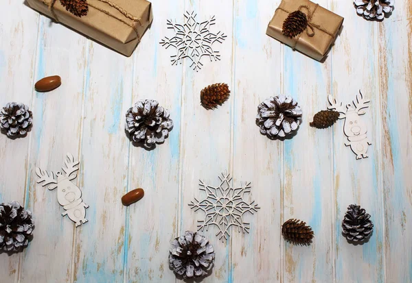 Christmas holidays composition on white wooden background. Craft boxes of gifts, wooden deer and snowflakes, fir cones, pine cones. Concept of happy (marry) christmas card.