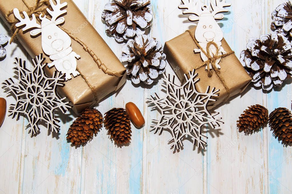 Christmas holidays composition on white wooden background. Craft boxes of gifts, wooden deer and snowflakes, fir cones, pine cones. Concept of happy (marry) christmas card.