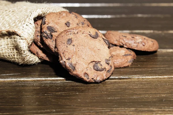 茶色の木製の背景に積み重ねられたチョコチップクッキー おいしいスナックのコンセプト 甘いデザート 選択的な焦点 クローズアップ — ストック写真