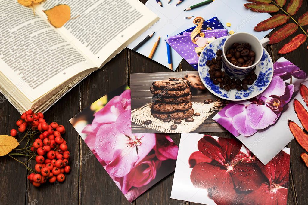 Autumn composition. Autumn mood. A blue cup of coffee with rowan berries and a book lie on a brown wooden box, decorated with autumn leaves.