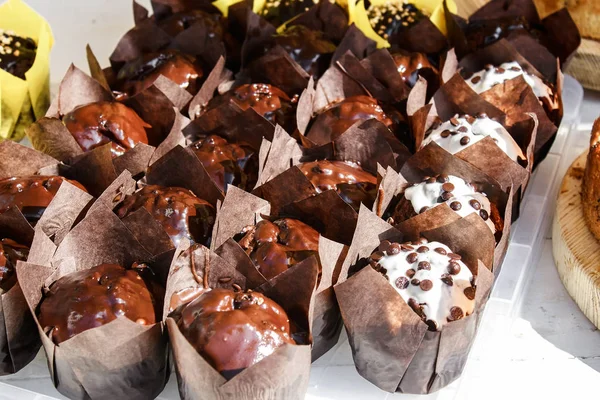 Chocolate muffins with chocolate chips in brown paper on a wooden background. Street food concept