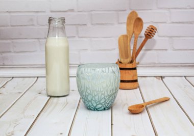Kefir, süt, mavi bardakta yoğurt beyaz arka planda tahta kaşıklar.