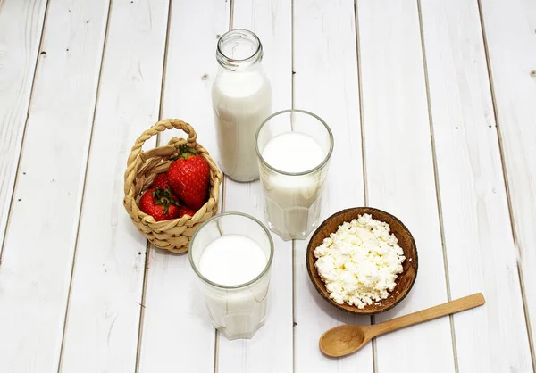 Kefir, milk, yogurt in bottle and blue glasses on white background whith strawberry and cocktail straws. — Stock Photo, Image