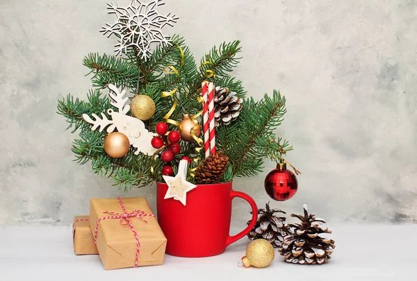 Noel ve yeni yıl kompozisyonu hediye kutuları, kırmızı bardaktaki köknar dalında altın toplar. Noel dekoru ve hediye kartı.
