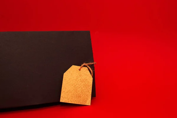 Bolso negro con etiqueta dorada sobre fondo rojo. Concepto de compras Viernes Negro. — Foto de Stock
