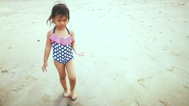 小さな女の子はビーチで遊ぶのに水泳の服を着ている — ストック動画