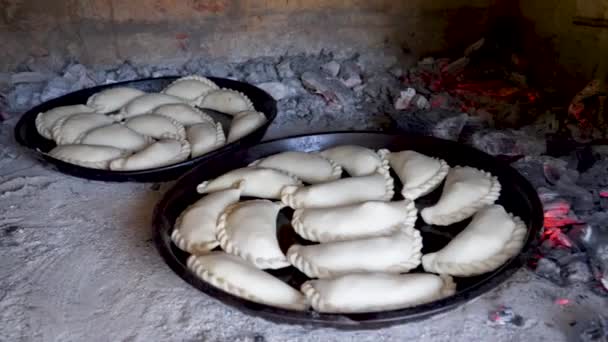 Twee dienbladen met traditionele Argentijnse empanadas koken in een kleioven — Stockvideo