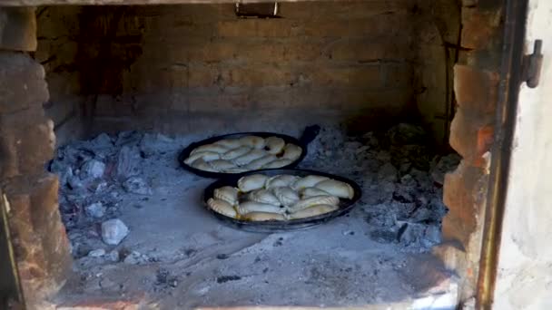 Twee dienbladen met traditionele Argentijnse empanadas koken in een kleioven. — Stockvideo
