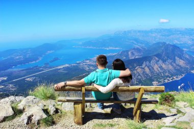 Erkek ve kız aşıkları, Karadağ'ın Lovcen dağındaki bir bankta oturuyorlar. Kotor Körfezi'ne bak.