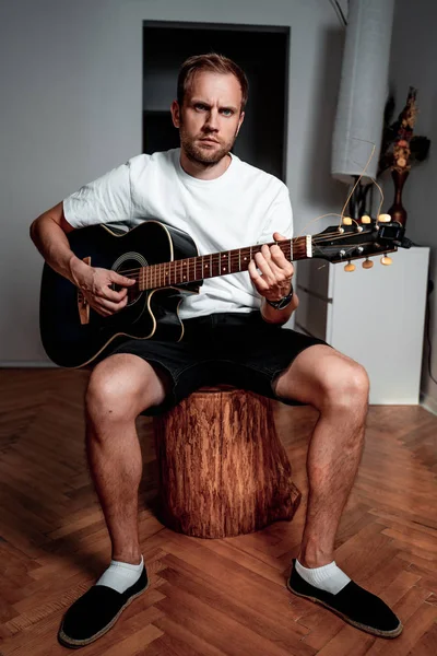 Beyaz bir T-shirt bir erkekte daire gitar çalıyor