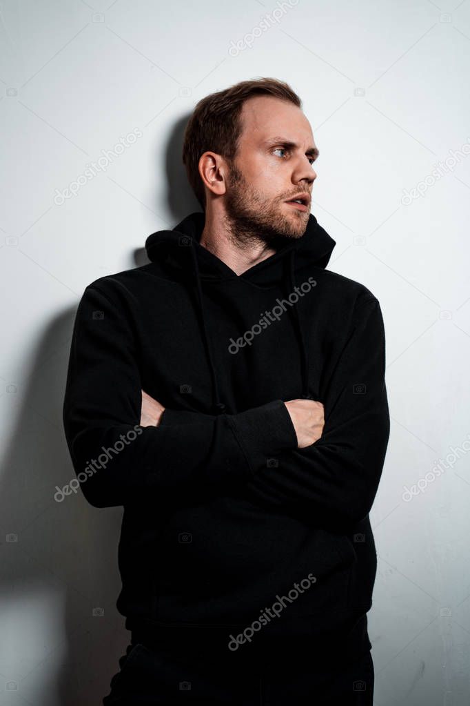 Man in a black sweater on a white wall background
