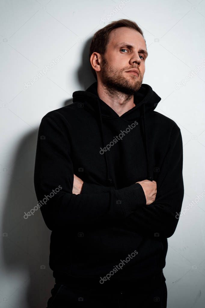 Man in a black sweater on a white wall background