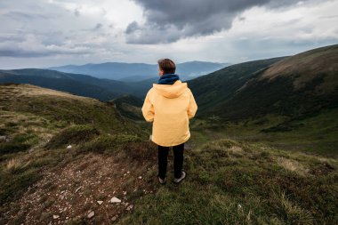 Sarı yağmurluk bir dağın tepesinde bir genç adam. Karpatlar, Ukrayna