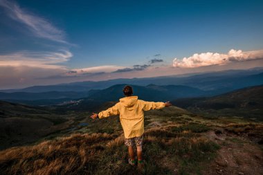 Sarı yağmurluk bir dağın tepesinde bir genç adam. Karpatlar, Ukrayna
