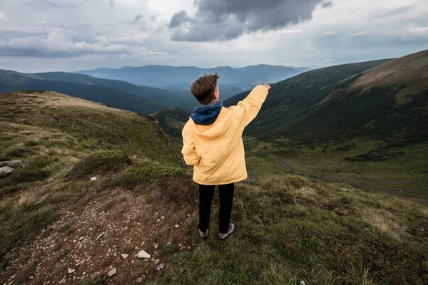 Sarı yağmurluk bir dağın tepesinde bir genç adam. Karpatlar, Ukrayna