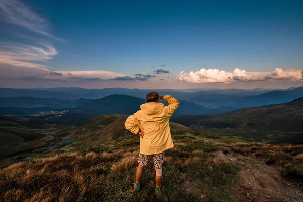 Sarı yağmurluk bir dağın tepesinde bir genç adam. Karpatlar, Ukrayna