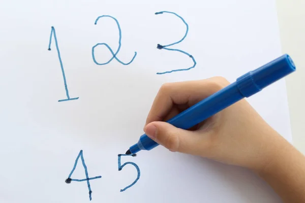 Hand detail of a 6 year-old child writing numbers