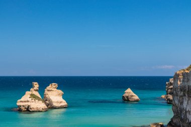 Torre dell 'Orso körfezi, yüksek uçurumları, Salento, Puglia, İtalya. Turkuaz deniz ve mavi gökyüzü, yazın güneşli bir gün. 