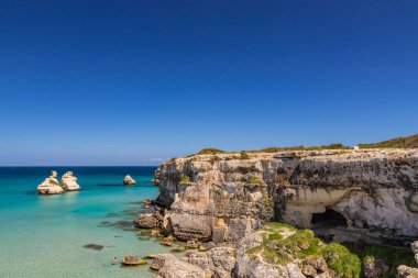 Torre dell 'Orso körfezi, yüksek uçurumları, Salento, Puglia, İtalya. Turkuaz deniz ve mavi gökyüzü, yazın güneşli bir gün. 