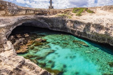 Roca Vecchia, Puglia, Salento, İtalya 'da arkeolojik alan ve turizm beldesi. Turkuaz deniz, berrak mavi gökyüzü, kayalar, güneş, yazın. Şiir Mağarası. Turistler fotoğraf çeker ve güneşlenir..