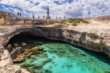 Roca Vecchia, Puglia, Salento, İtalya 'da arkeolojik alan ve turizm beldesi. Turkuaz deniz, berrak mavi gökyüzü, kayalar, güneş, yazın. Şiir Mağarası. Turistler fotoğraf çeker ve güneşlenir..