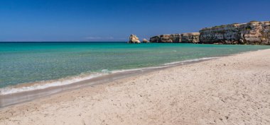 Torre dell 'Orso körfezi, yüksek uçurumları, Salento, Puglia, İtalya. Turkuaz deniz ve mavi gökyüzü, yazın güneşli bir gün. Güzel beyaz kumsal. Yığınların adı İki Kız Kardeş..