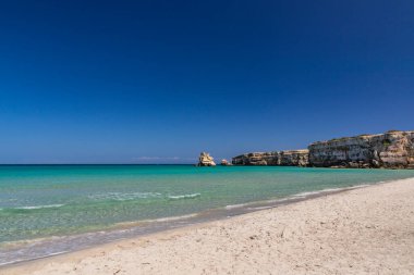 Torre dell 'Orso körfezi, yüksek uçurumları, Salento, Puglia, İtalya. Turkuaz deniz ve mavi gökyüzü, yazın güneşli bir gün. Güzel beyaz kumsal. Yığınların adı İki Kız Kardeş..