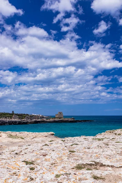 Roca Vecchia, Puglia, Salento, İtalya 'da arkeolojik alan ve turizm beldesi. Turkuaz deniz, berrak mavi gökyüzü, kayalar, güneş, yazın. 16. yüzyıl gözcü kulesi. Beyaz bulutlar ve güçlü rüzgar.