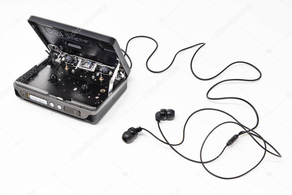 Vintage audio player. Old fashioned portable cassette player, cult object, icon and symbol of the 80s and 90s. Headphones isolated on white background. Open door.