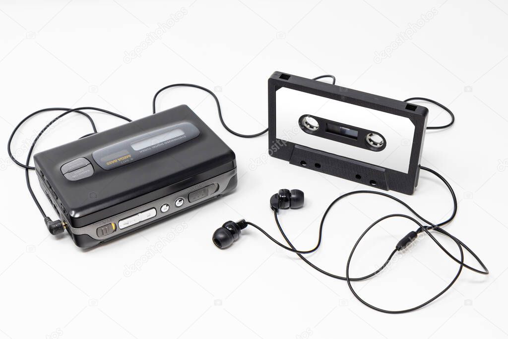 Vintage audio player. Old fashioned portable cassette player, cult object, icon and symbol of the 80s and 90s. Blank audio tape and headphones isolated on white background.