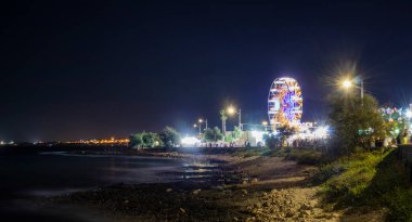 Torre Vado 'da, yazın, gece denizin muhteşem manzarası. Turistler için eğlenceli bir yer. Dönme dolap, tezgah, market, restoranlar ve fast food. İtalya, Puglia, Lecce, Salento.
