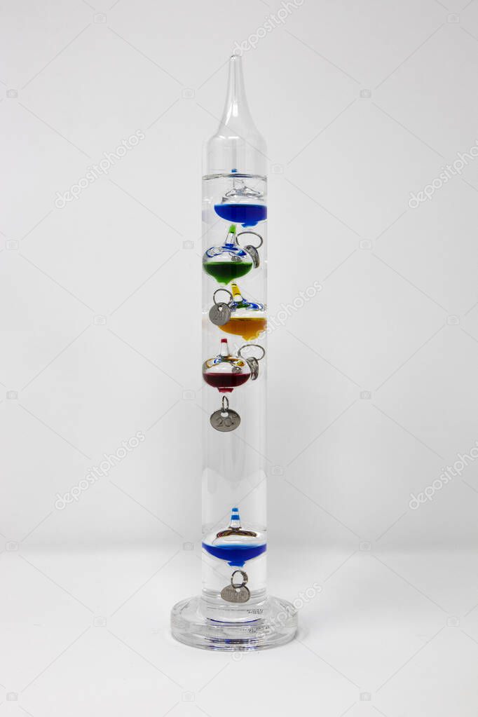 Galileo Galilei thermometer is a thermometer made of a sealed glass cylinder containing a clear liquid and several glass vessels of varying density. Isolated on white background.