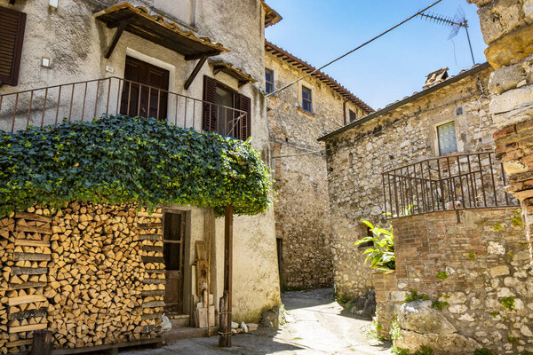 June 30, 2019 - Stifone, Umbria, Terni, Italy - A glimpse of the small village of Stifone, on the Nera river. An alley between the stone houses. The wood piled up for the winter. Pergola with ivy.
