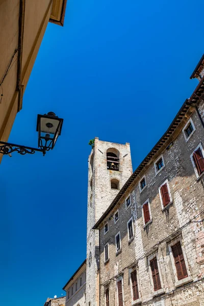 stock image The Palazzo del Podesta, in Piazza dei Priori in the ancient medieval village of Narni. The stone bell tower and the clock. Umbria, Terni, Italy. The blue sky on a summer day.