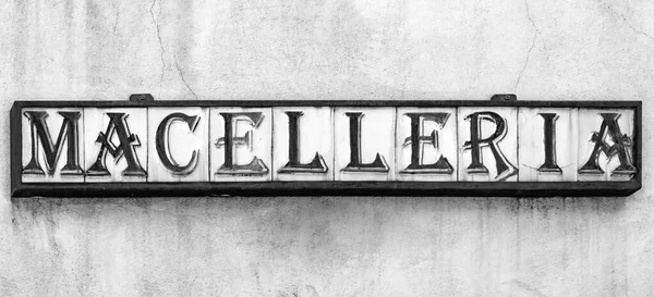 An ancient craft sign of an Italian butcher shop. Ceramic tiles inserted in a metal structure, compose the word \