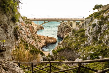 Ciolo köprüsü iki yüksek uçurumu birbirine bağlar. Santa Maria di Leuca yakınlarındaki Gagliano del Capo 'da bir deniz girişi. Kırmızı ve turuncu gün batımı. Bir kış akşamında. Salento, Puglia, İtalya.